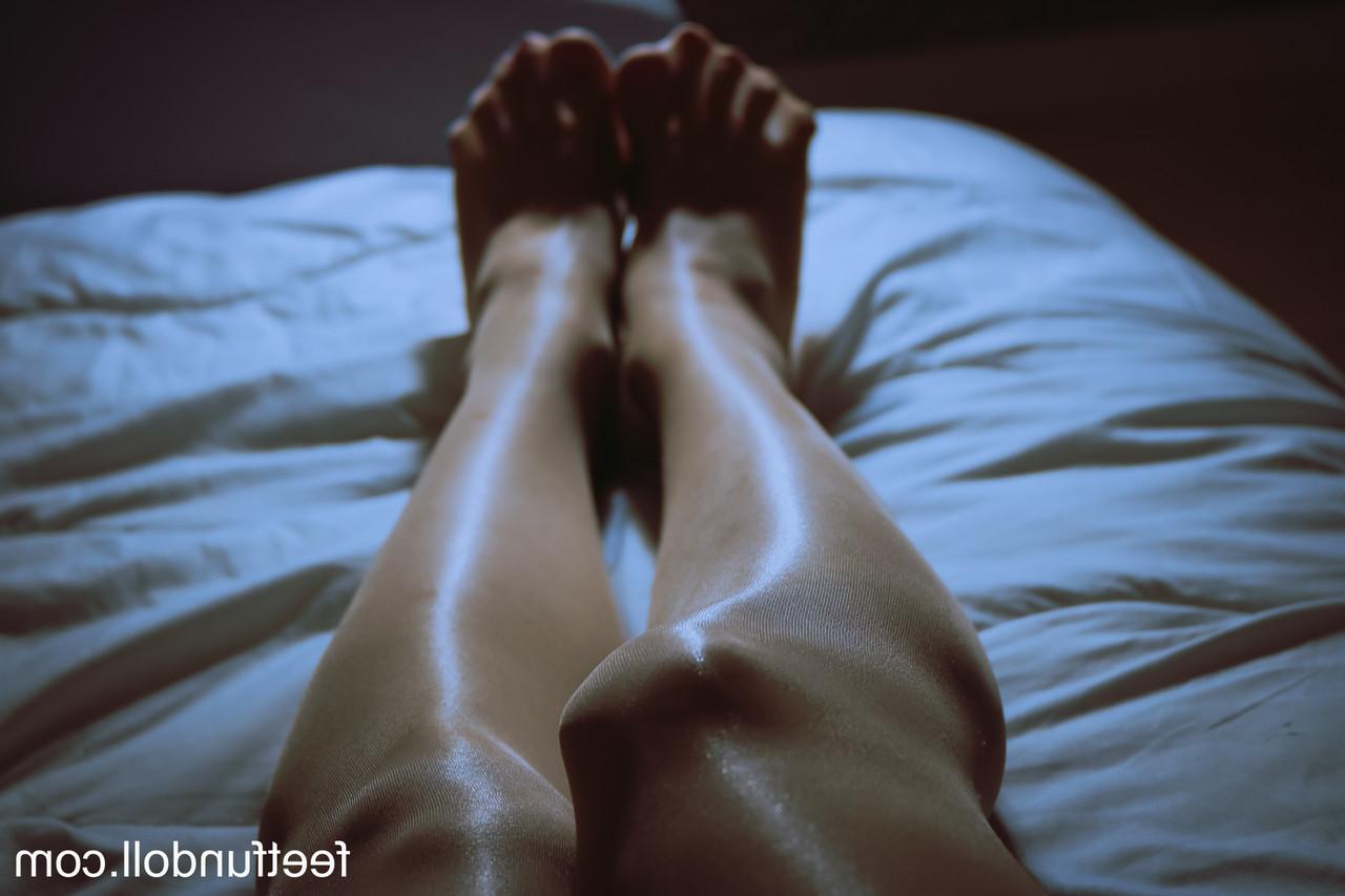 15P Lisa Dove, une jeune femme nue, montre ses jambes sexy et sa chatte taillée sur son lit.