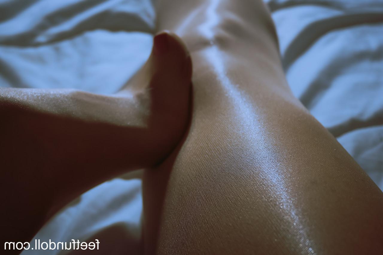 15P Lisa Dove, une jeune femme nue, montre ses jambes sexy et sa chatte taillée sur son lit.