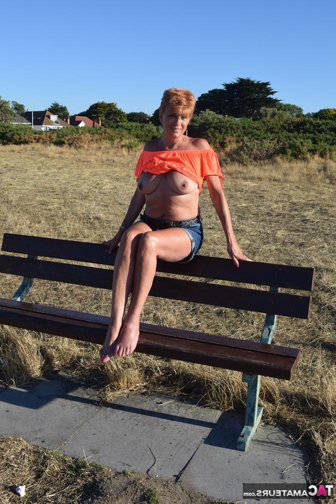 20P La madura pelirroja Dimonty muestra sus tetas en un banco de un campo rural