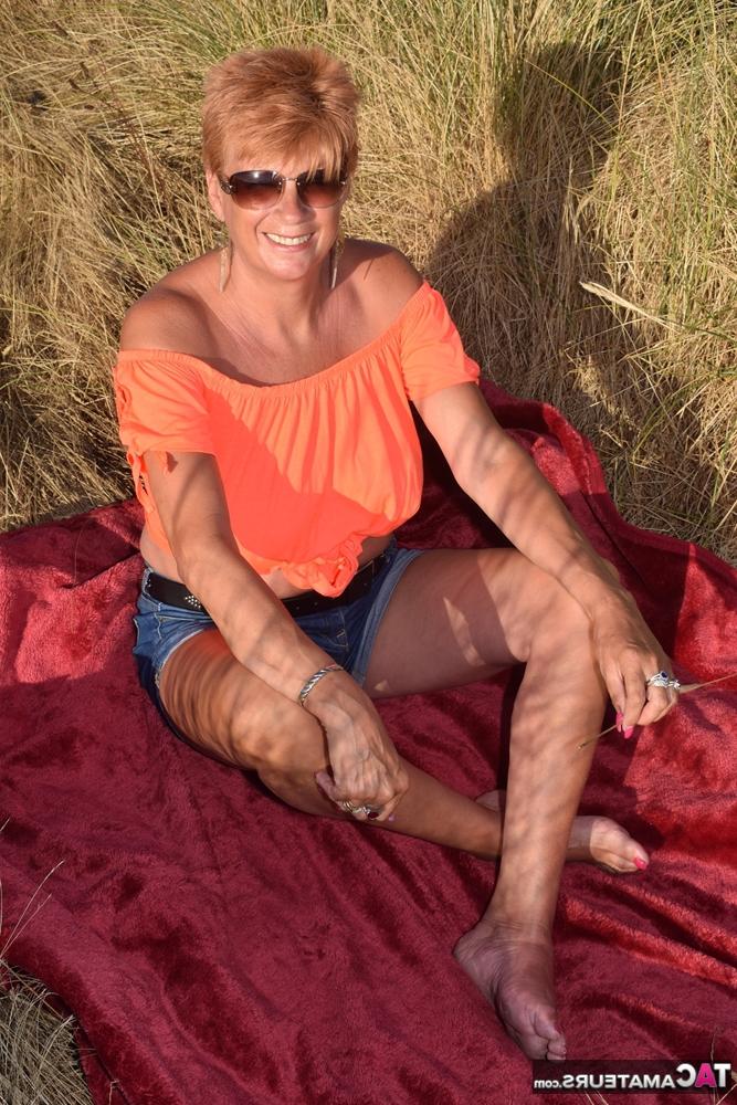 20P La madura pelirroja Dimonty muestra sus tetas en un banco de un campo rural