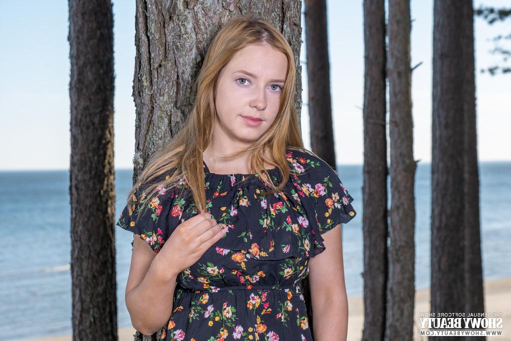 20P La jolie jeune Sara dévoile ses seins pleins en se mettant nue sous un arbre en bord de mer.
