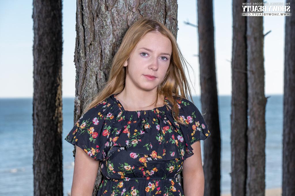 20P La jolie jeune Sara dévoile ses seins pleins en se mettant nue sous un arbre en bord de mer.