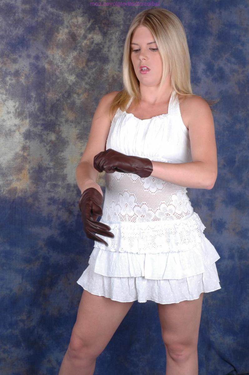 15P Mujer rubia se pone guantes de cuero marrón mientras usa un vestido blanco