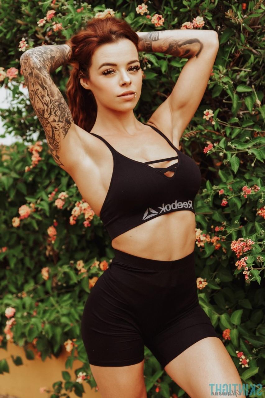 12P La rousse tatouée Mia Stryker enlève ses vêtements de sport devant des buissons en fleurs