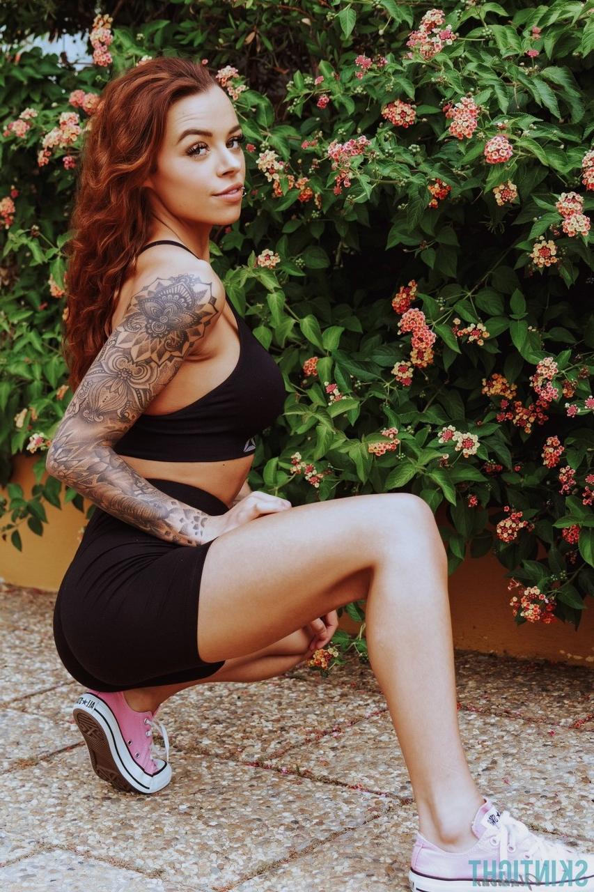 12P La rousse tatouée Mia Stryker enlève ses vêtements de sport devant des buissons en fleurs