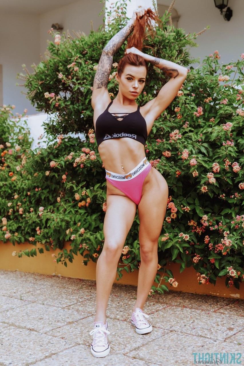 12P La rousse tatouée Mia Stryker enlève ses vêtements de sport devant des buissons en fleurs