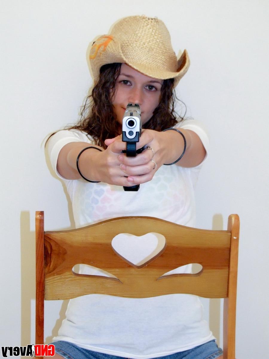 12P Encantadora adolescente morena empuña una pistola mientras se desnuda en calzado