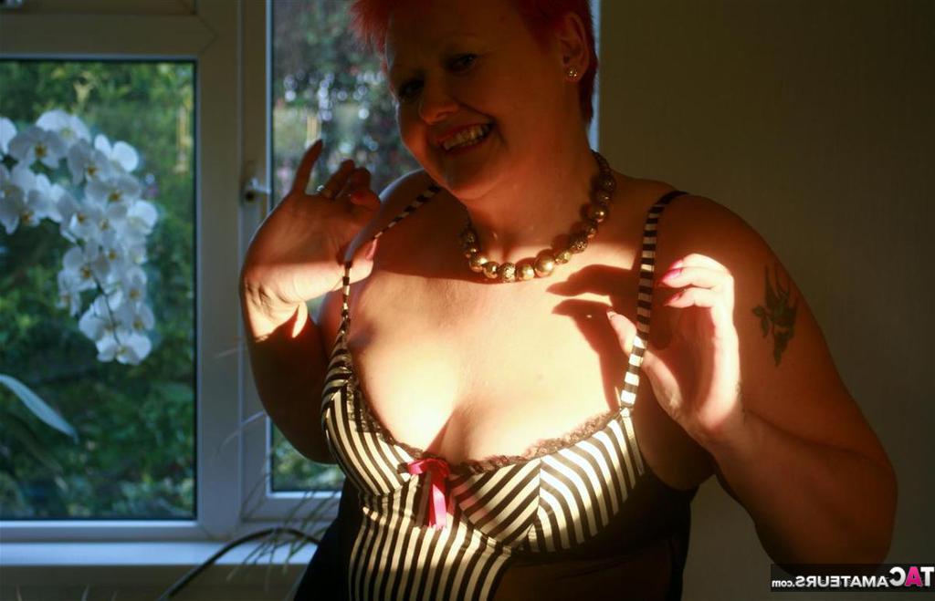 20P Older redhead Valgasmic Exposed shows her big butt and bald cunt atop a bed