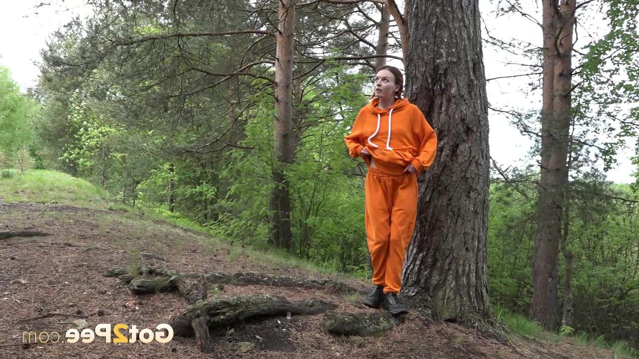 15P La jolie fille Jeanna se fait surprendre en train de pisser dans les bois contre un arbre.