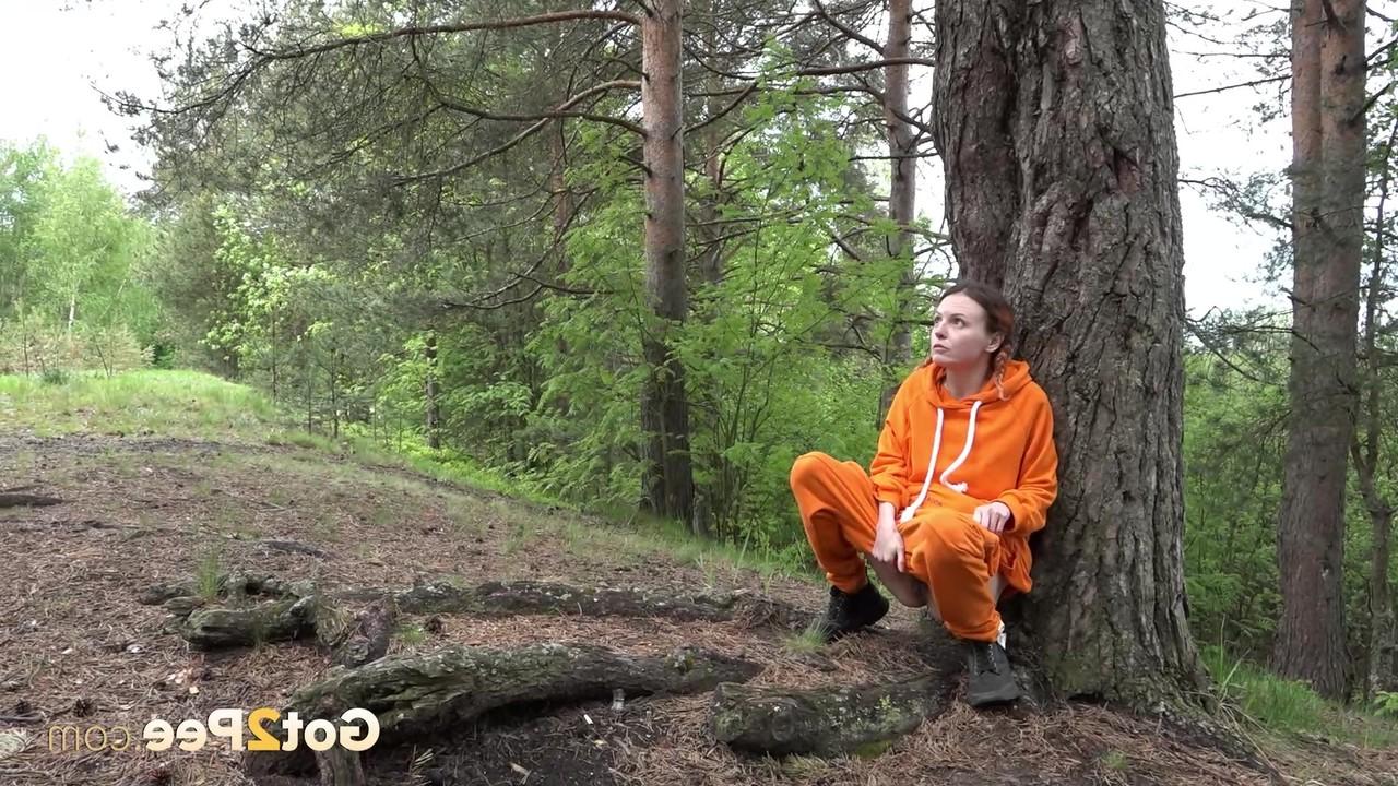 15P La jolie fille Jeanna se fait surprendre en train de pisser dans les bois contre un arbre.