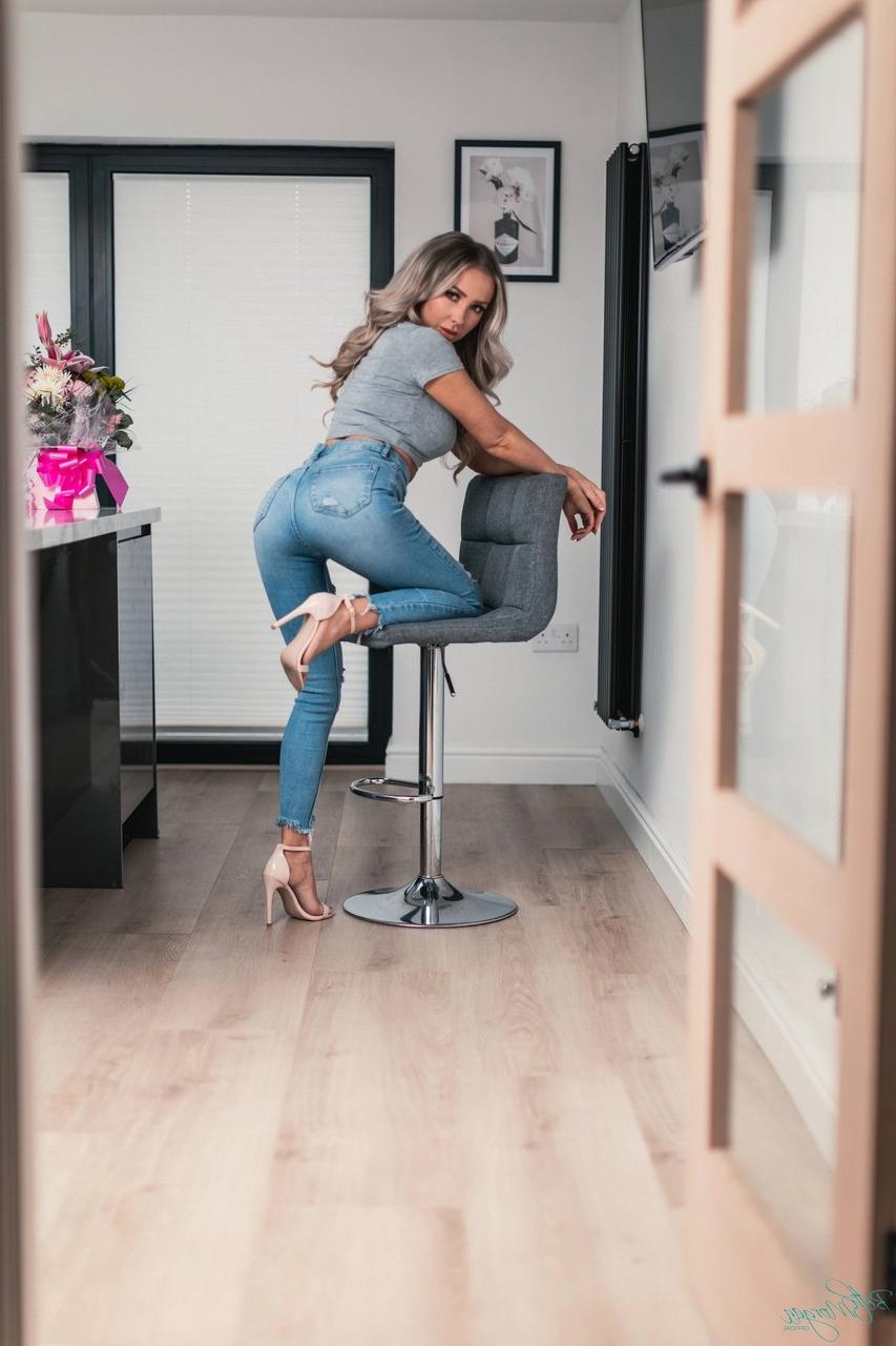 12P Beth Morgan, blonde platine, se déshabille avec un string et des talons de manière sexy.