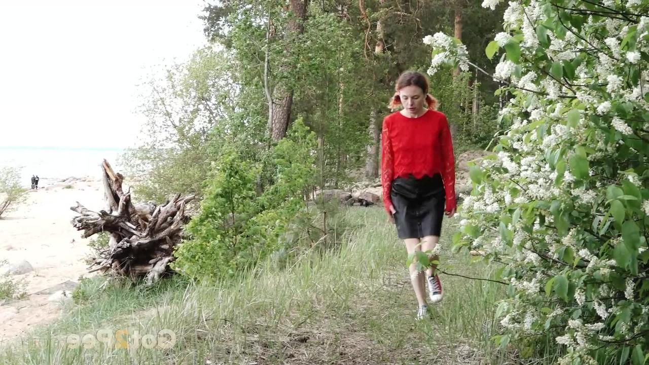 15P Kaukasisches Mädchen hockt hinter einem Busch, um dringend zu pinkeln