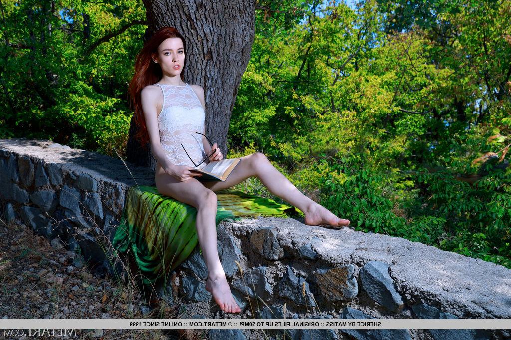 18P Young redheaded Sherice gets totally naked on stone wall under a tree