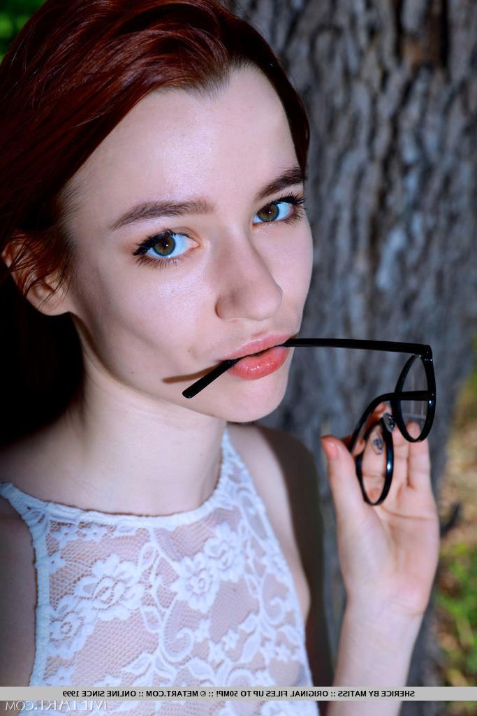 18P Young redheaded Sherice gets totally naked on stone wall under a tree
