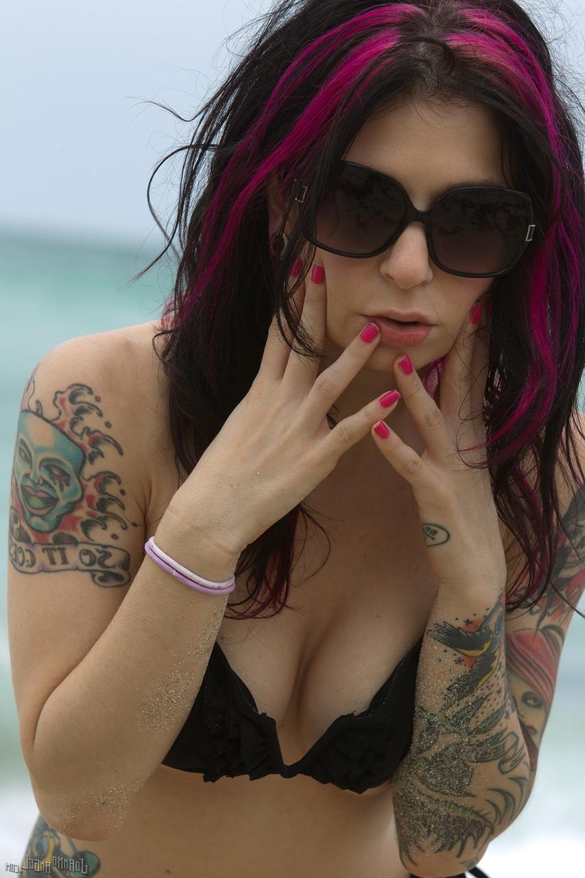 17P Modelo tatuada posa desnuda en la playa con bikini y gafas de sol