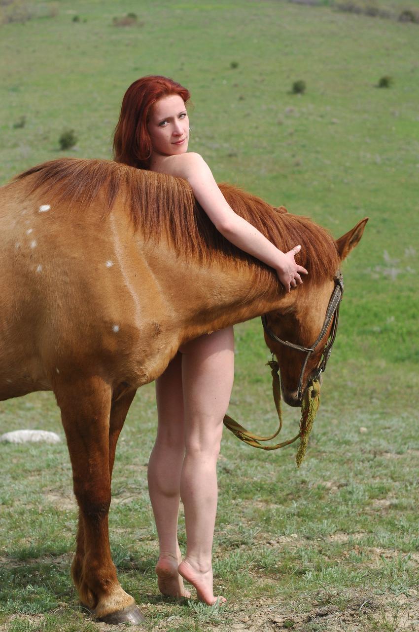 20P La joven pelirroja Klara A posa completamente desnuda sobre un enorme caballo al aire libre