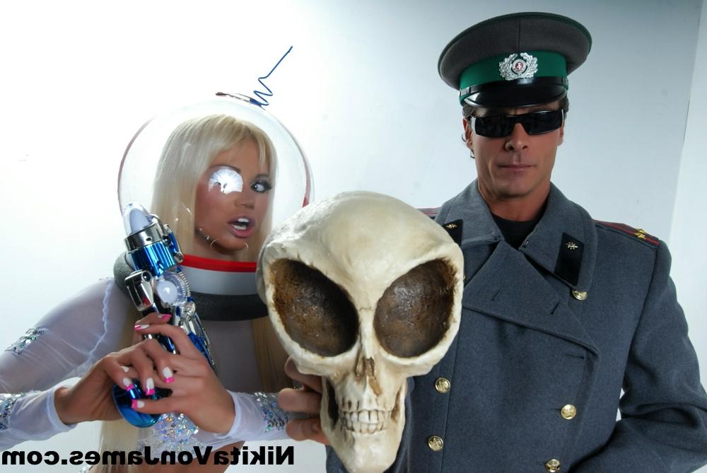 16P Hot blonde Nikita Von James models futuristic apparel next to a military man