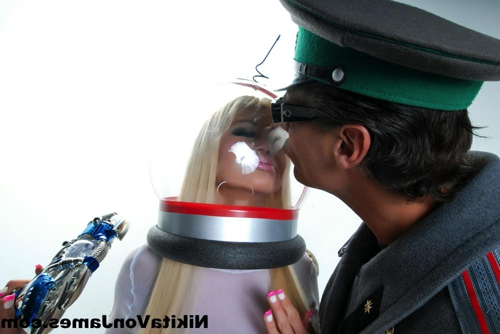 16P Hot blonde Nikita Von James models futuristic apparel next to a military man