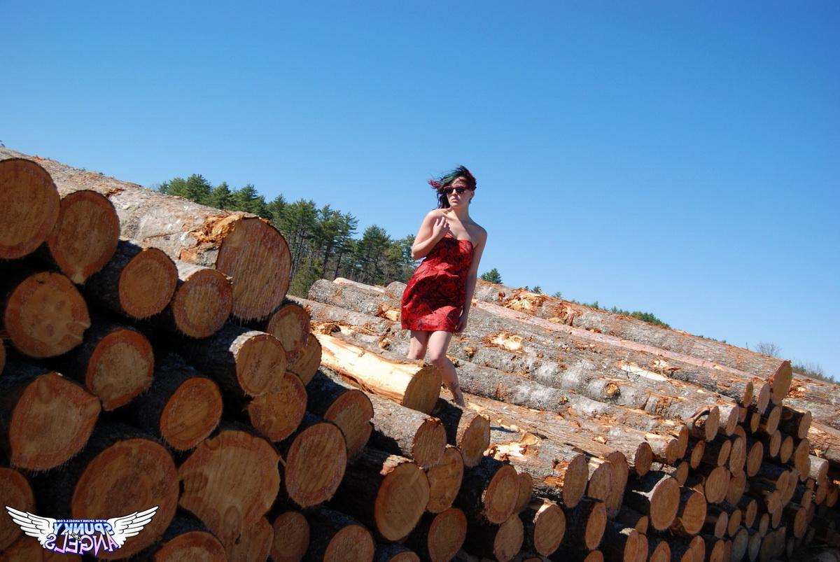 12P Amateur chick Sabrina teases in front of freshly cut logs in a field
