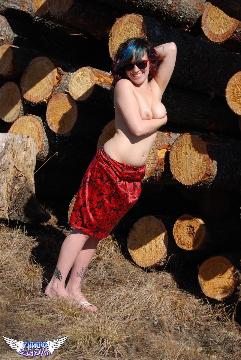 12P Amateur chick Sabrina teases in front of freshly cut logs in a field