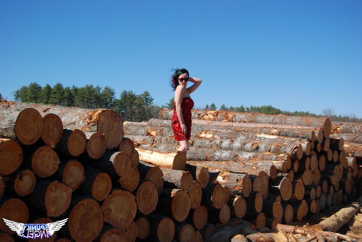 12P Amateur chick Sabrina teases in front of freshly cut logs in a field
