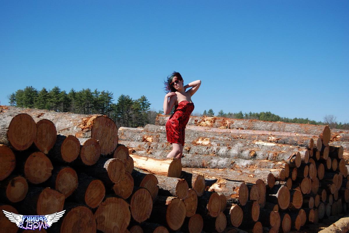 12P Amateur chick Sabrina teases in front of freshly cut logs in a field
