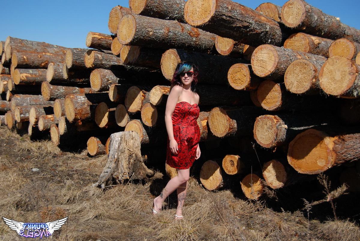 12P Amateur chick Sabrina teases in front of freshly cut logs in a field