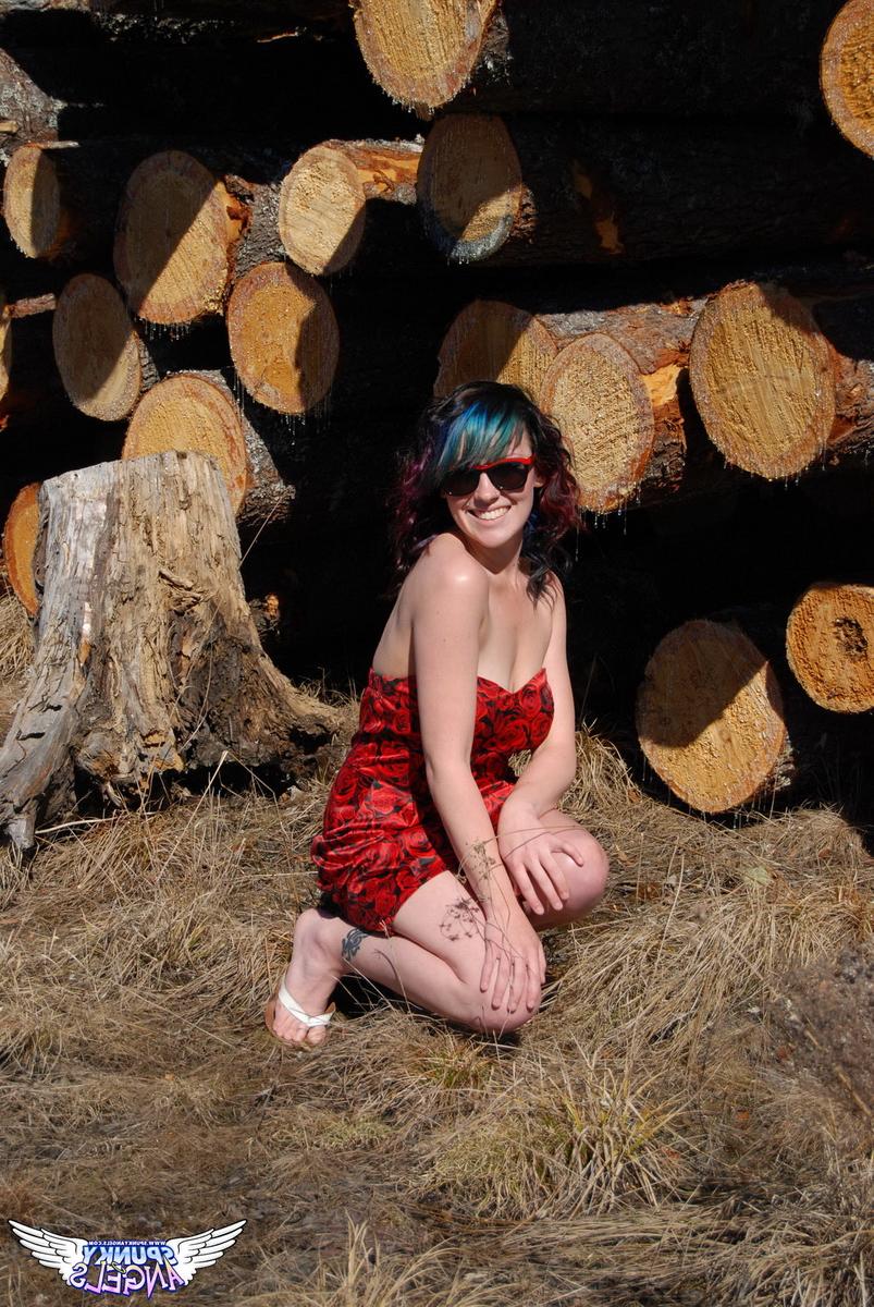 12P Amateur chick Sabrina teases in front of freshly cut logs in a field