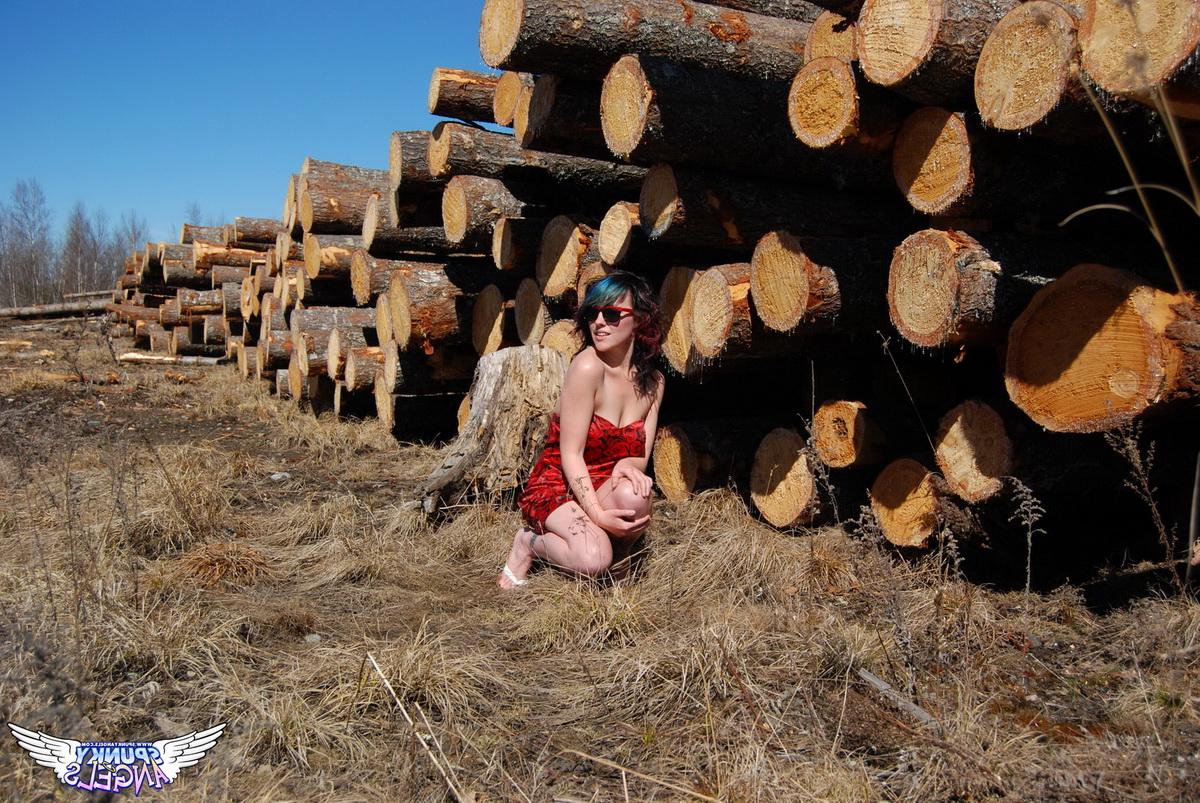 12P Amateur chick Sabrina teases in front of freshly cut logs in a field
