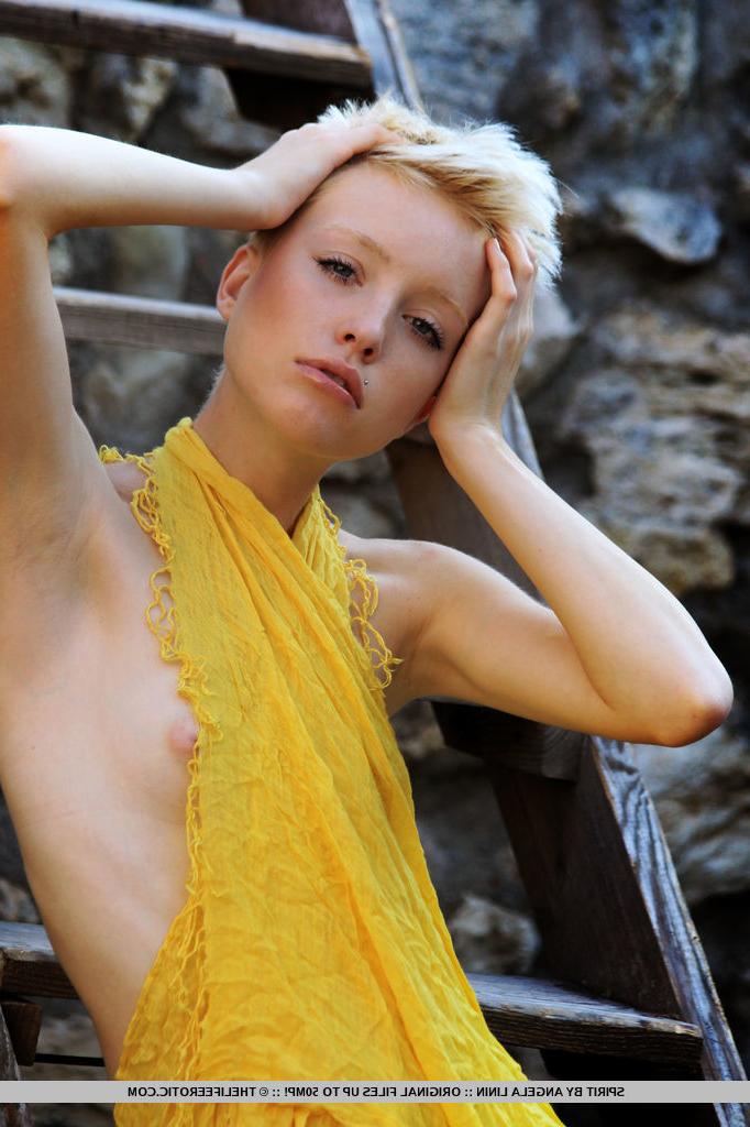 16P Une fille blonde aux cheveux courts enlève sa robe jaune pour des poses nues dans une fosse en pierre
