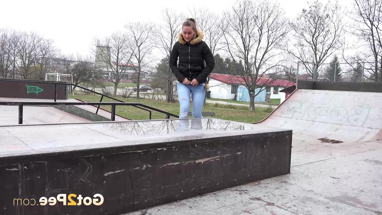 15P La niña blanca Naomi Bennet orina en un charco en un parque de patinaje durante el día.