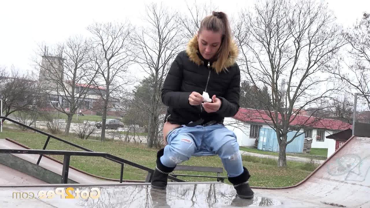 15P La niña blanca Naomi Bennet orina en un charco en un parque de patinaje durante el día.