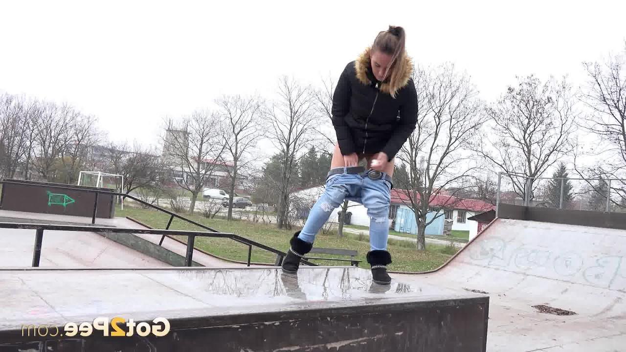 15P La niña blanca Naomi Bennet orina en un charco en un parque de patinaje durante el día.