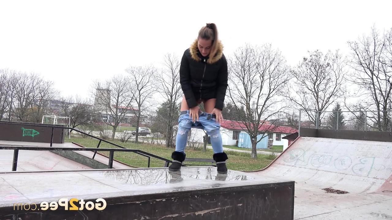 15P La niña blanca Naomi Bennet orina en un charco en un parque de patinaje durante el día.