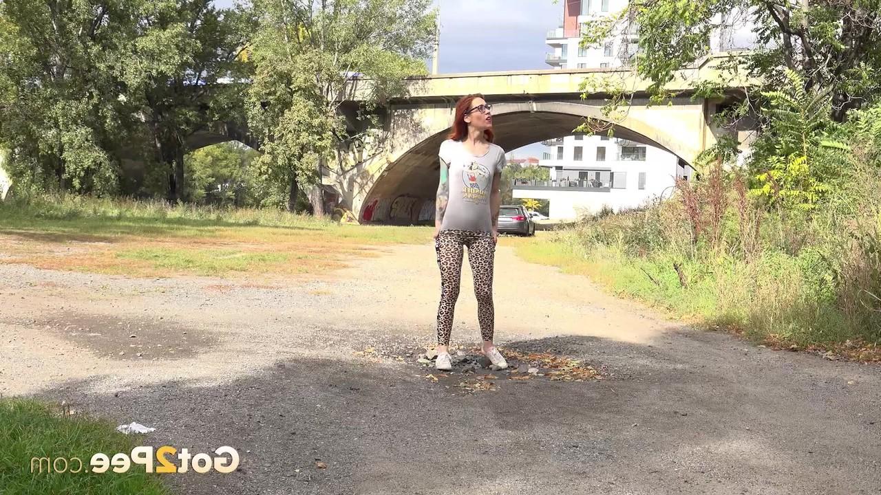 15P A ruiva Sandra faz xixi em uma poça em uma estrada de cascalho