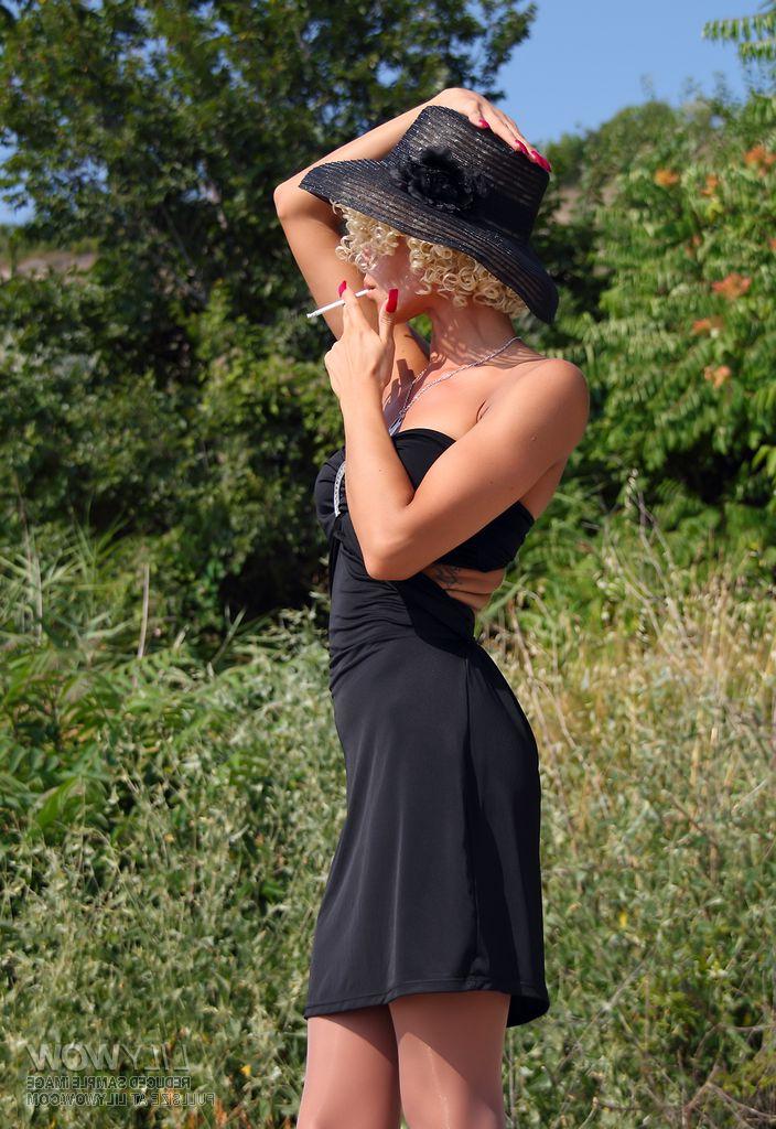 15P Long legged girl with curly blonde hair smokes during an upskirt tease shoot