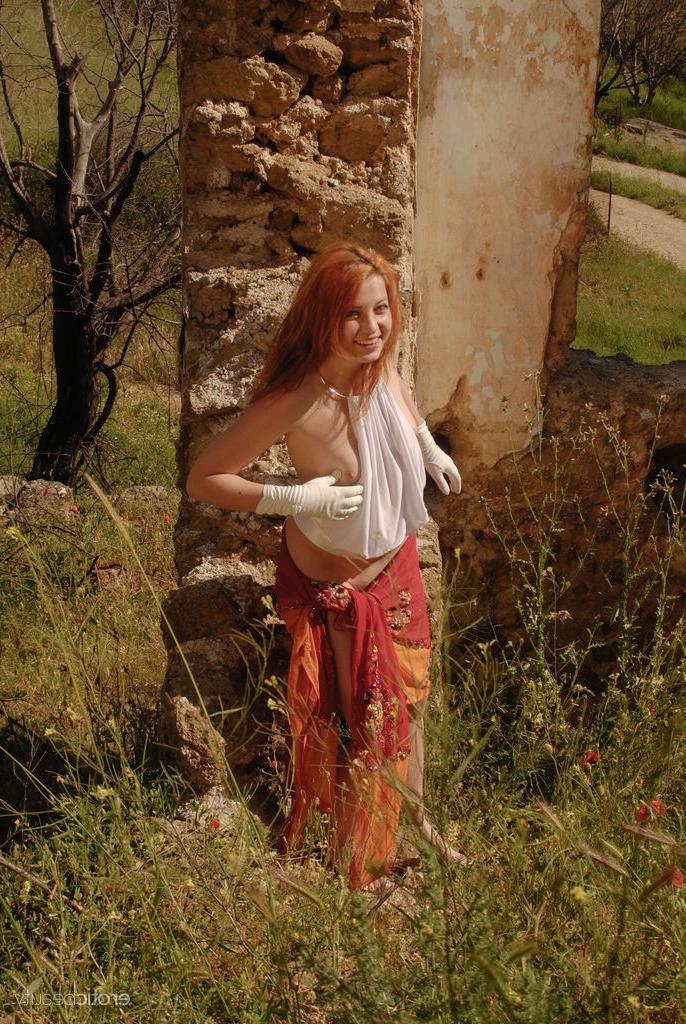 16P Aelit, la rousse naturelle, se déshabille avec des gants blancs près d'un immeuble en ruine.