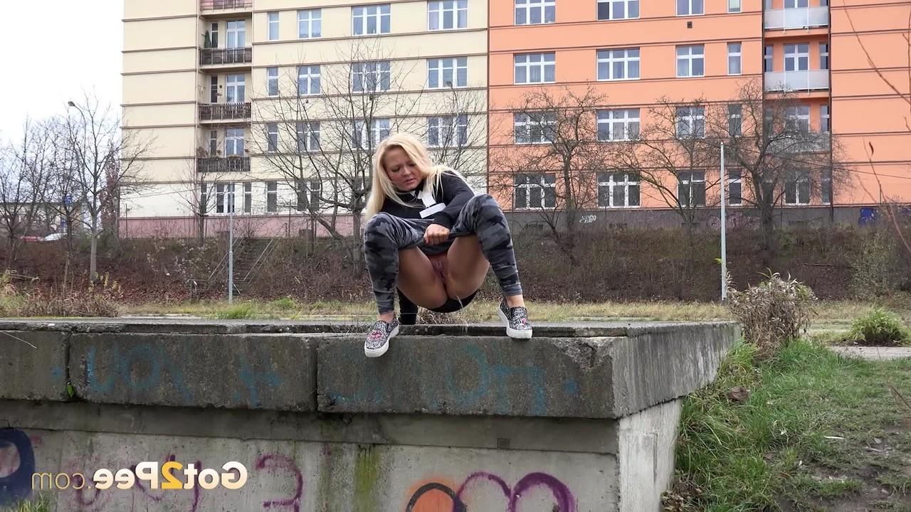 15P A loira Jenna Lovely mija em uma plataforma de concreto em vista de um prédio