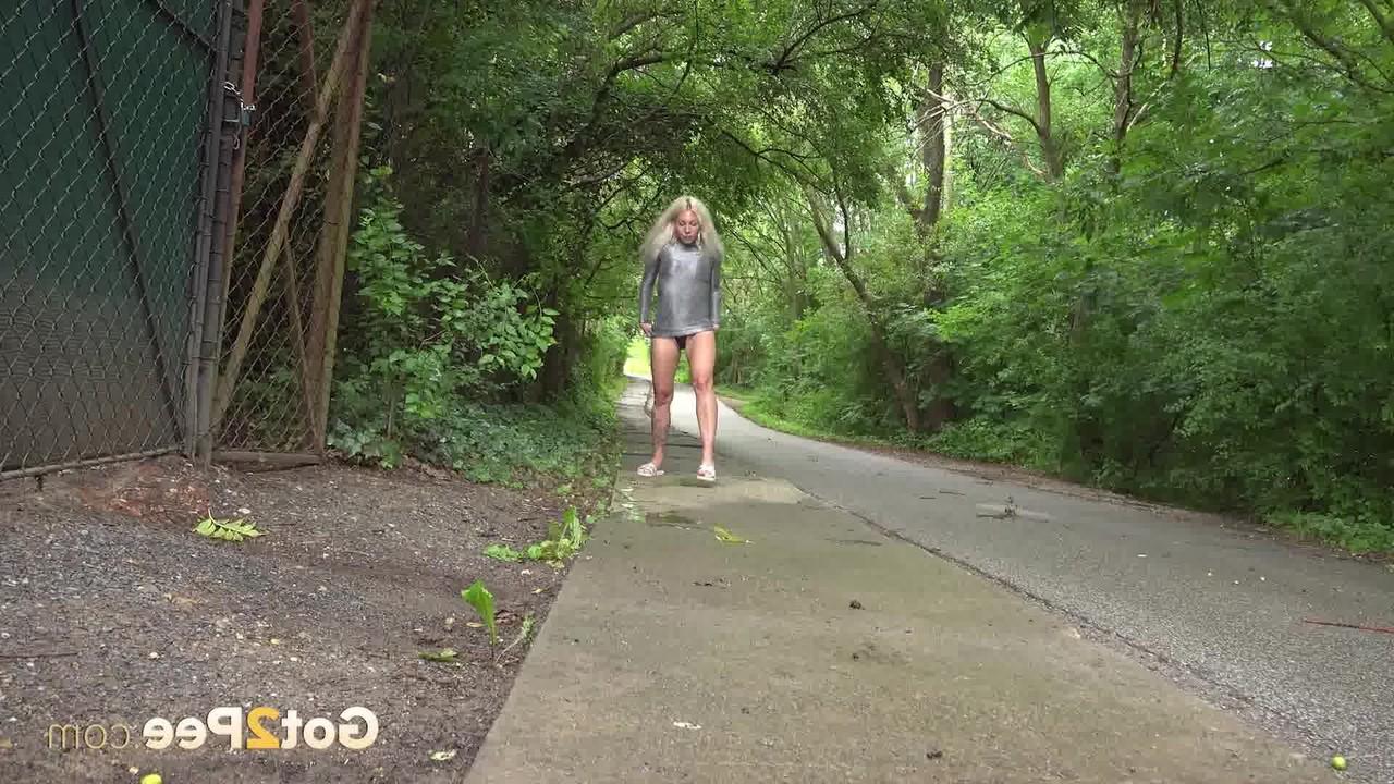 15P A loira Caroli se agacha antes de mijar em uma estrada pavimentada ladeada de árvores