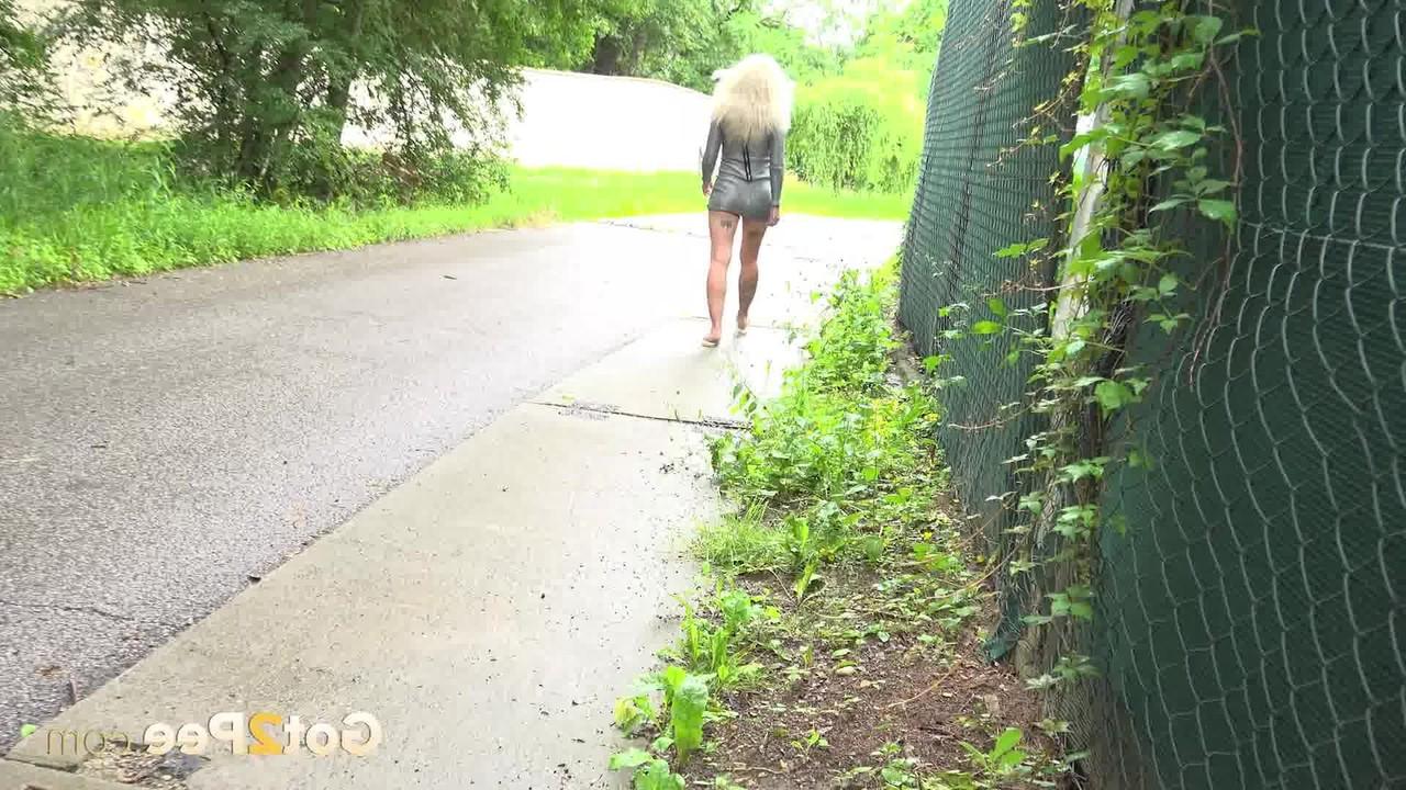 15P A loira Caroli se agacha antes de mijar em uma estrada pavimentada ladeada de árvores