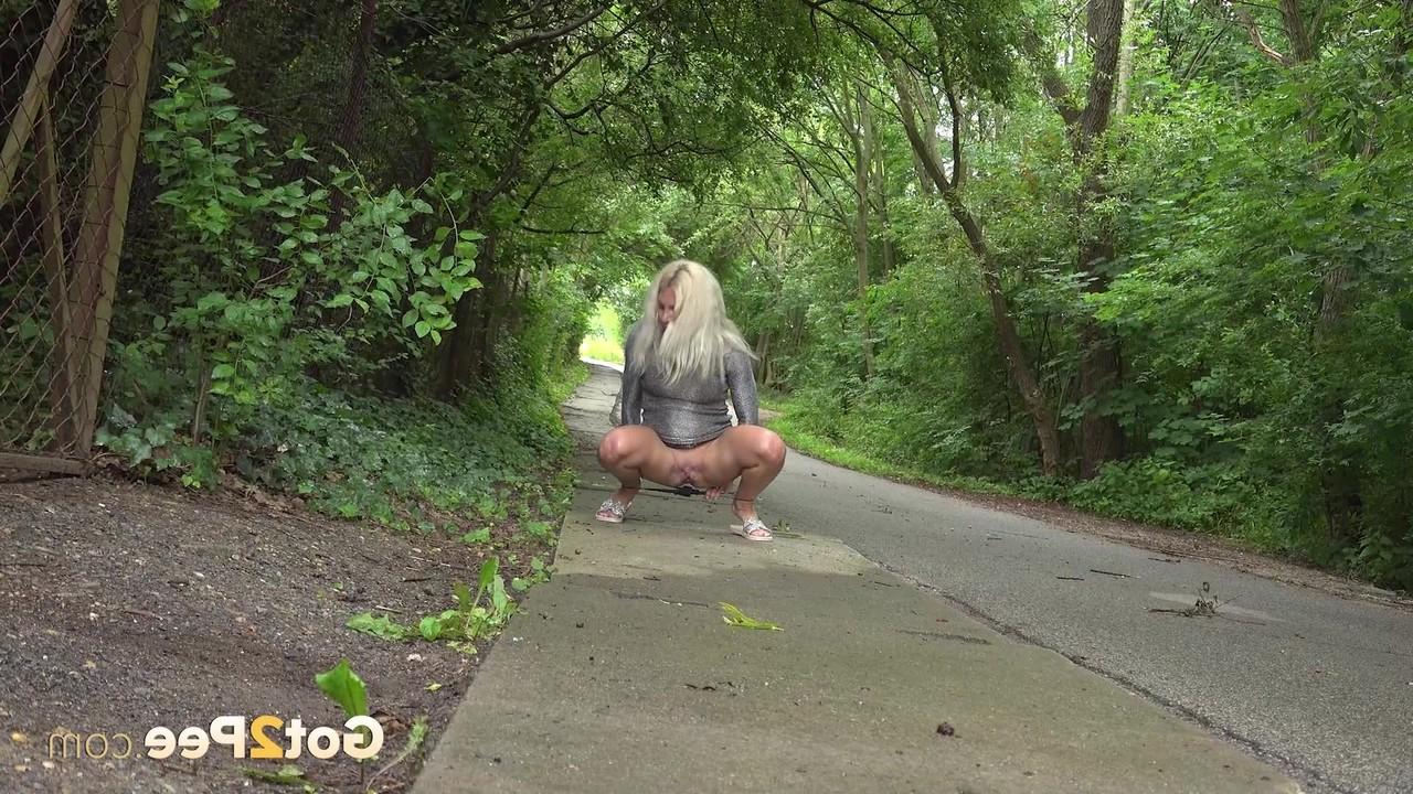 15P A loira Caroli se agacha antes de mijar em uma estrada pavimentada ladeada de árvores