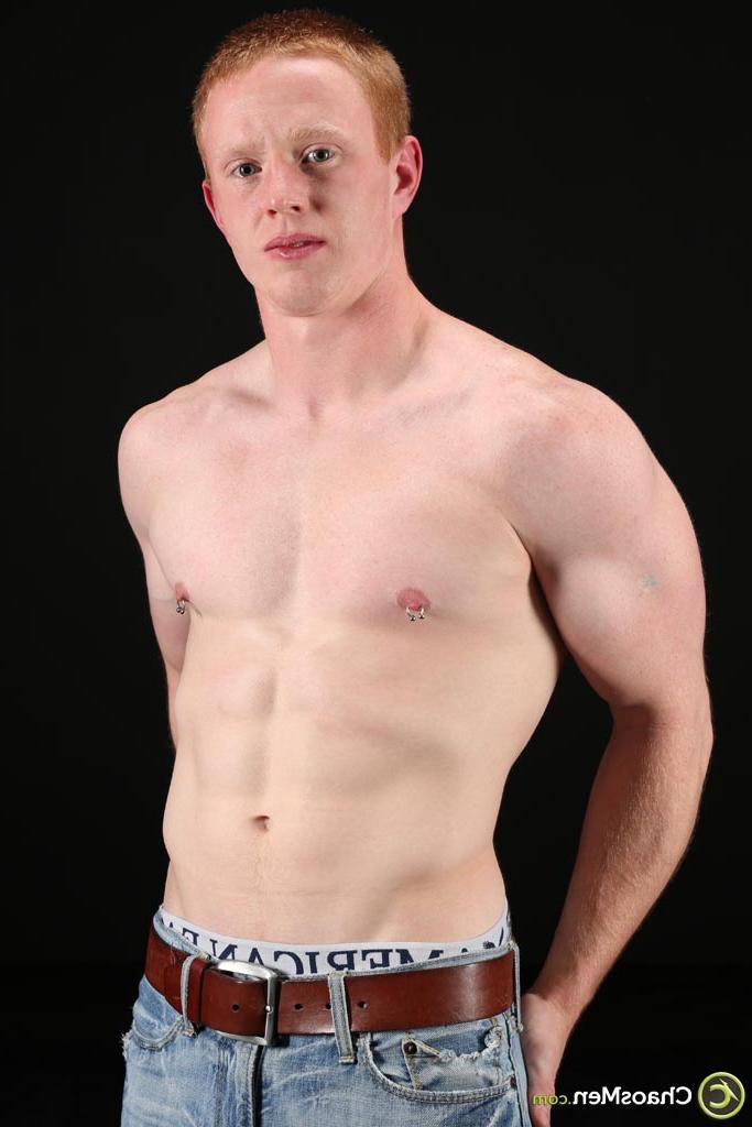20P Gay redhead Brant exposes his massive cock and poses nude on a green couch