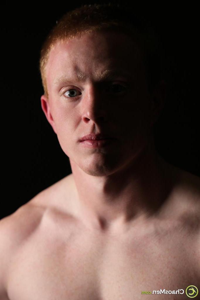 20P Gay redhead Brant exposes his massive cock and poses nude on a green couch