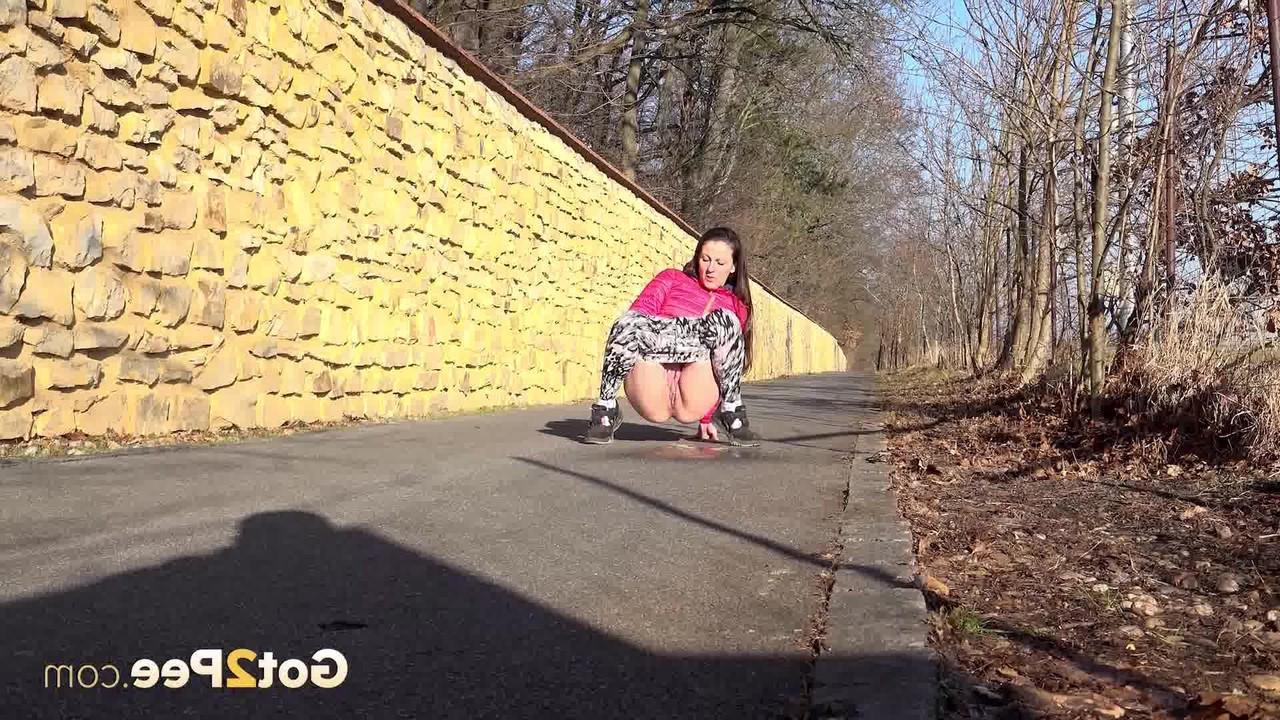 15P A garota caucasiana Valentina Ross faz xixi em uma estrada pavimentada durante o dia
