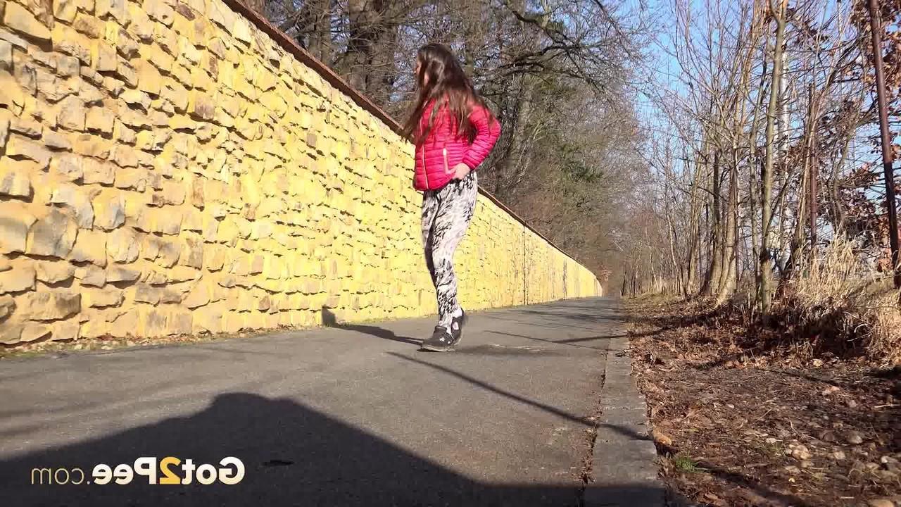 15P A garota caucasiana Valentina Ross faz xixi em uma estrada pavimentada durante o dia