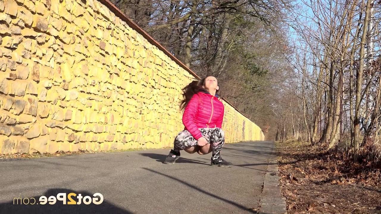 15P A garota caucasiana Valentina Ross faz xixi em uma estrada pavimentada durante o dia