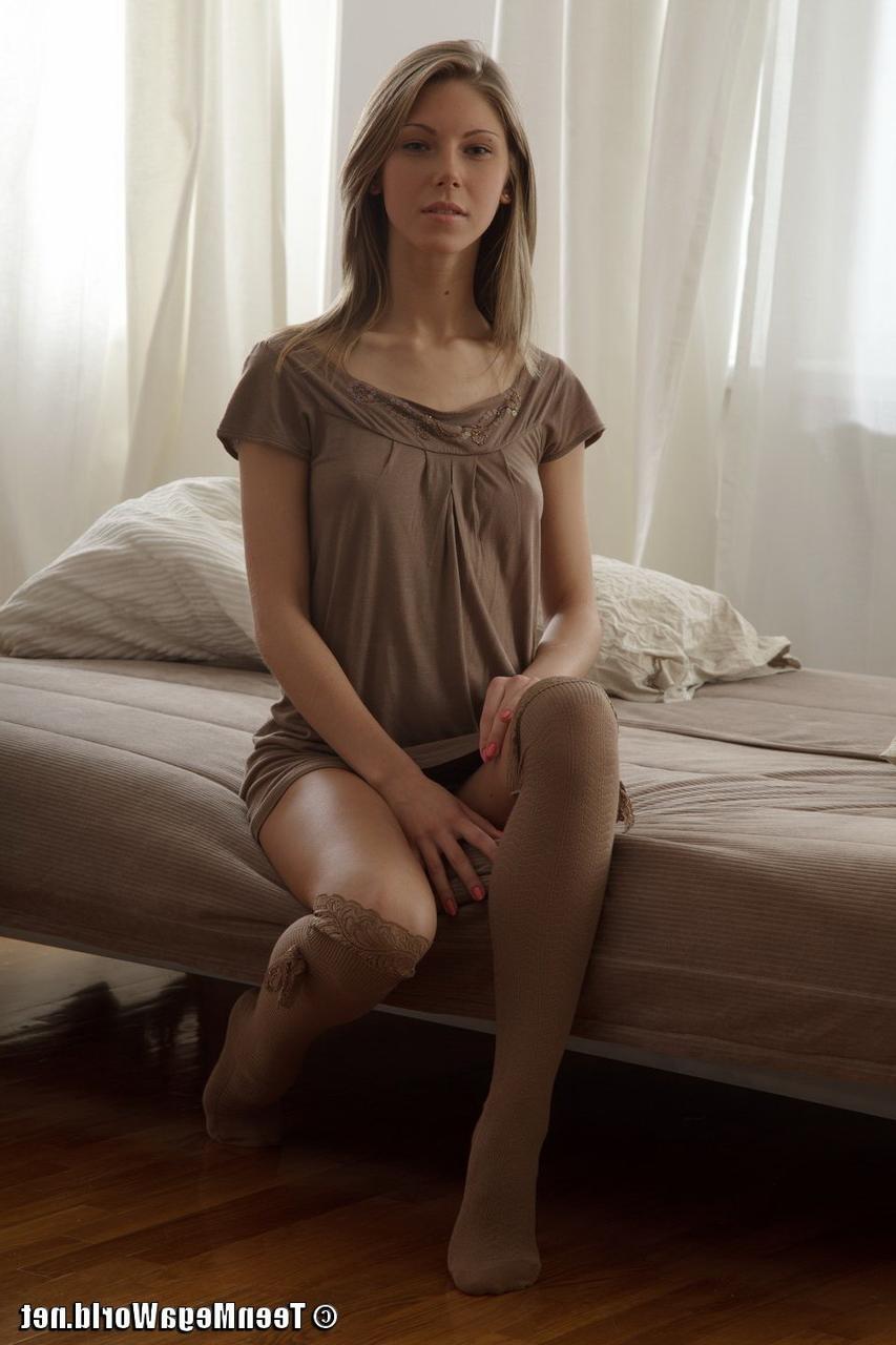 15P La petite jeune Anjelica attire l'attention sur sa chatte parfaitement lisse nue.
