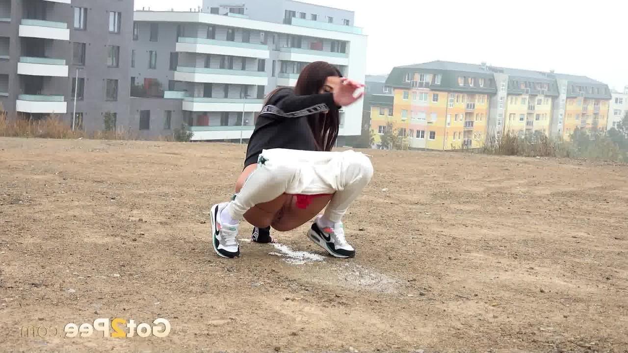 15P Pretty brunette Maddi Black pulls down her pants to piss in a wide open lot