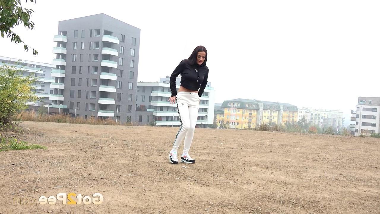 15P Pretty brunette Maddi Black pulls down her pants to piss in a wide open lot
