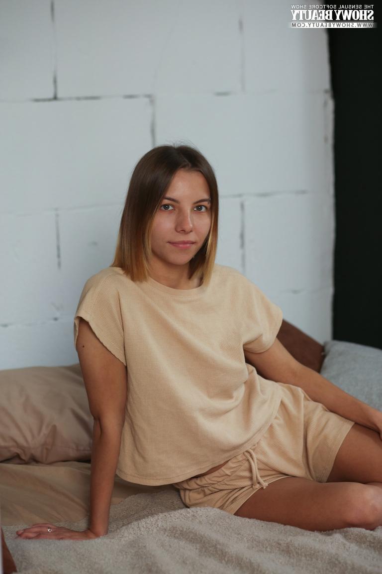 20P La jolie jeune Julie croise ses jambes nues tout en se mettant totalement nue sur un lit.
